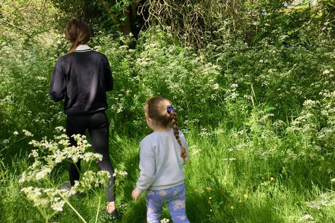 young child follows older child in forest